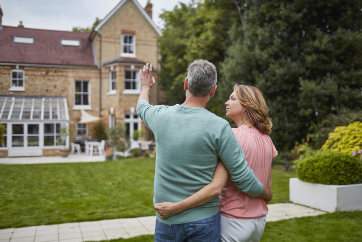 Mature couple standing in front of house