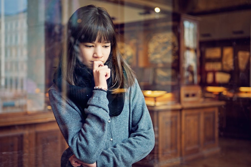 A girl with scarf, thinking of something while looking outside